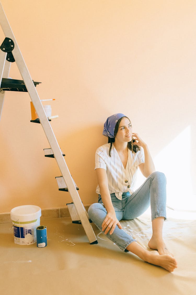 Woman Sitting On The Floor With Paint Bucket Beside Her