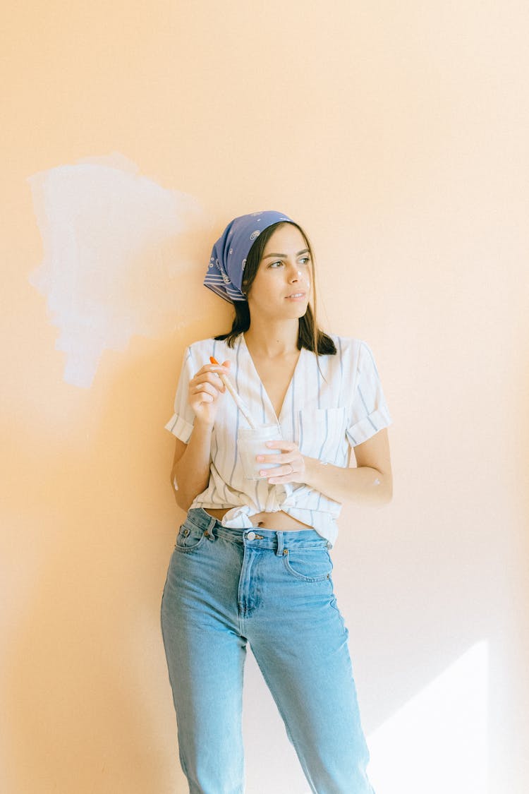 Woman Holding A Paint Brush And A Clear Container With White Paint