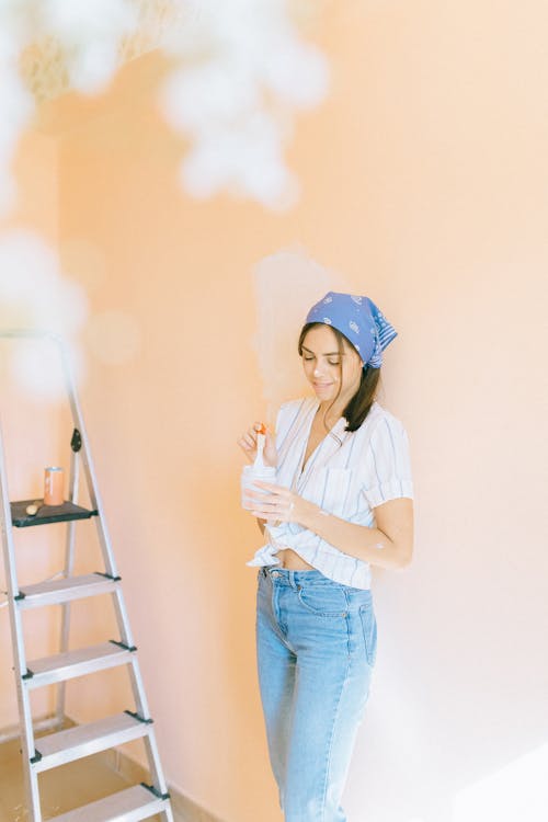 Free Woman in Striped Shirt and Denim Jeans Standing near a Wall Stock Photo