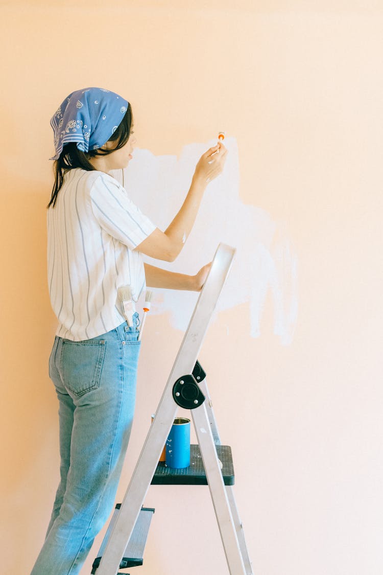 Woman Standing On Stepladder While Painting Wall