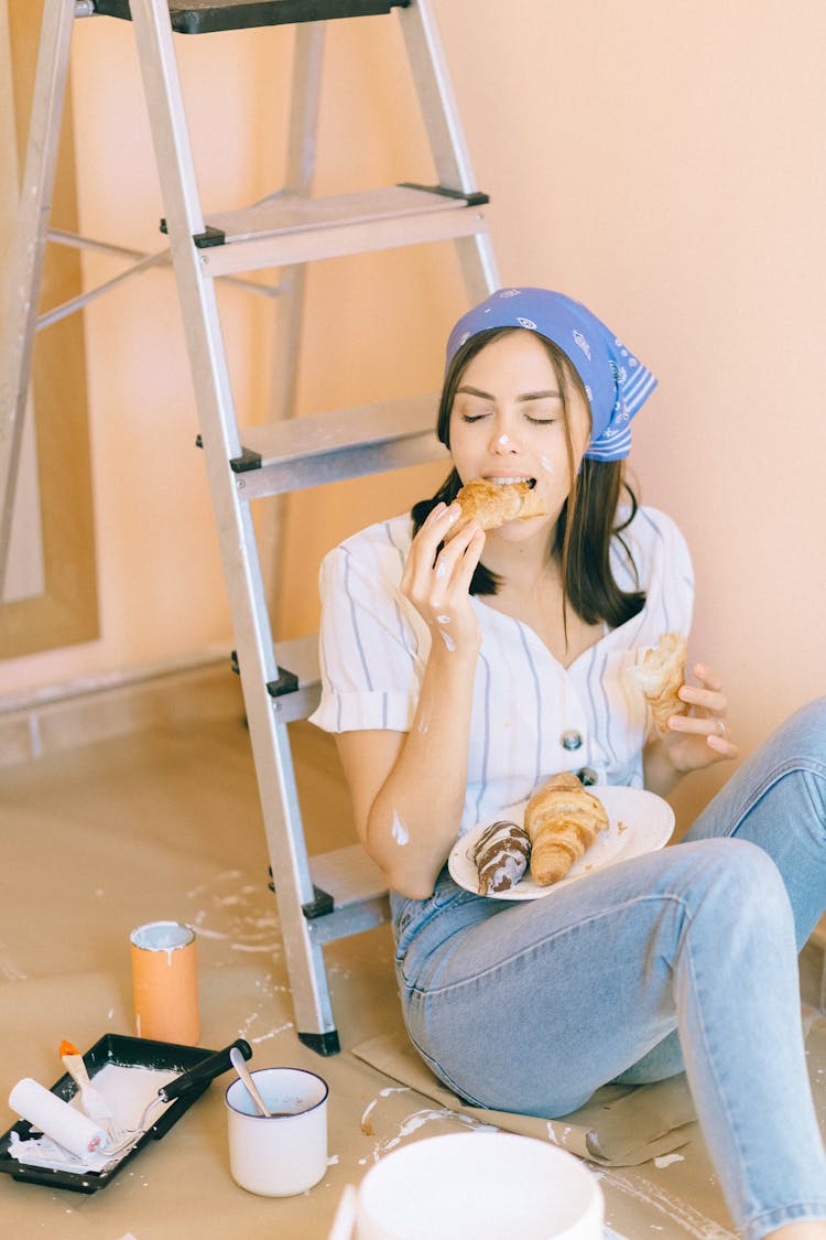 Person Sitting On The Floor While Eating Croissant