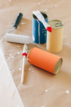 Upcycled paint cans with brushes and rollers.