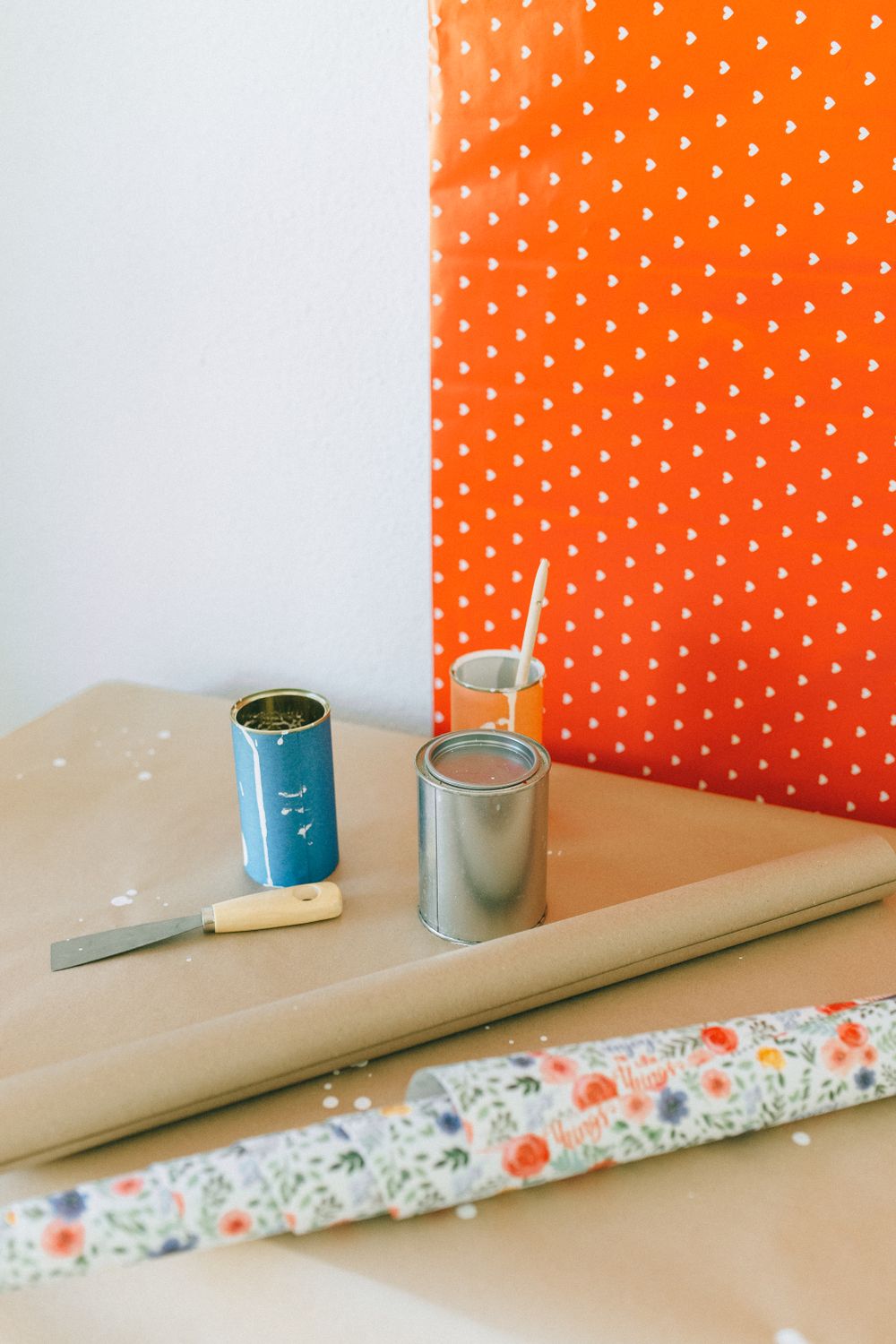 Wallpaper rolls, paint cans, and brushes laid out on a worktable