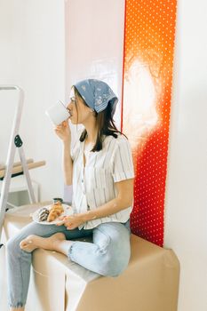一名女子坐在室内桌旁，喝着咖啡，享用羊角面包