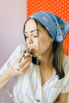 一位戴着头巾的年轻女子正在享用美味的糕点，周围遍布油漆，营造出有趣的场景