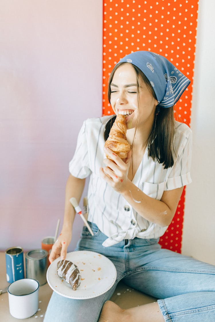 Woman Happily Eating A Croissant
