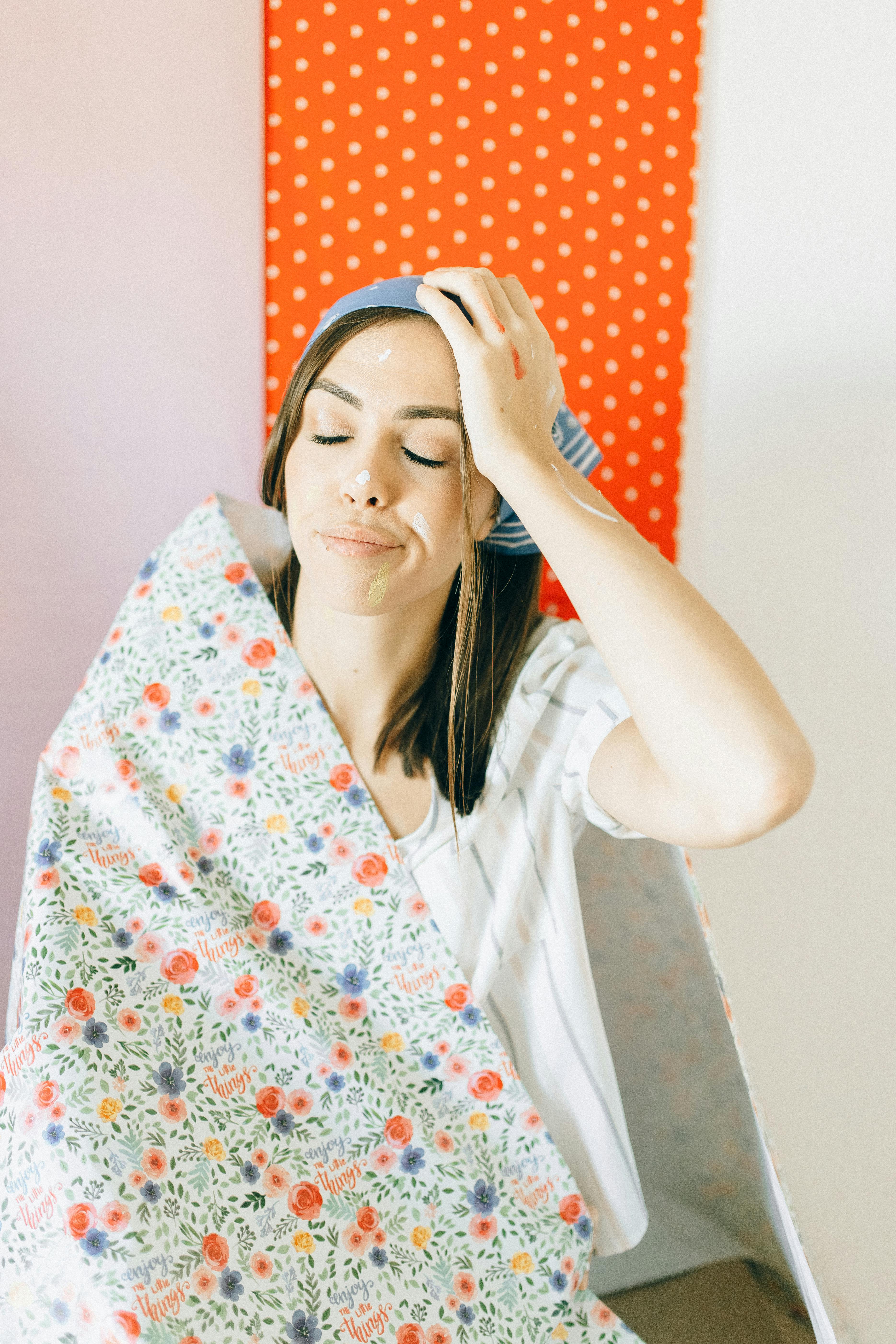 woman in white shirt covering her face with white and red floral blanket