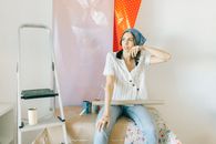 一名妇女坐在室内，拿着壁纸和梯子，计划房屋装修