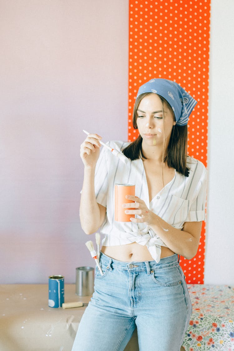 Woman Holding A Paint Brush And An Orange Cup