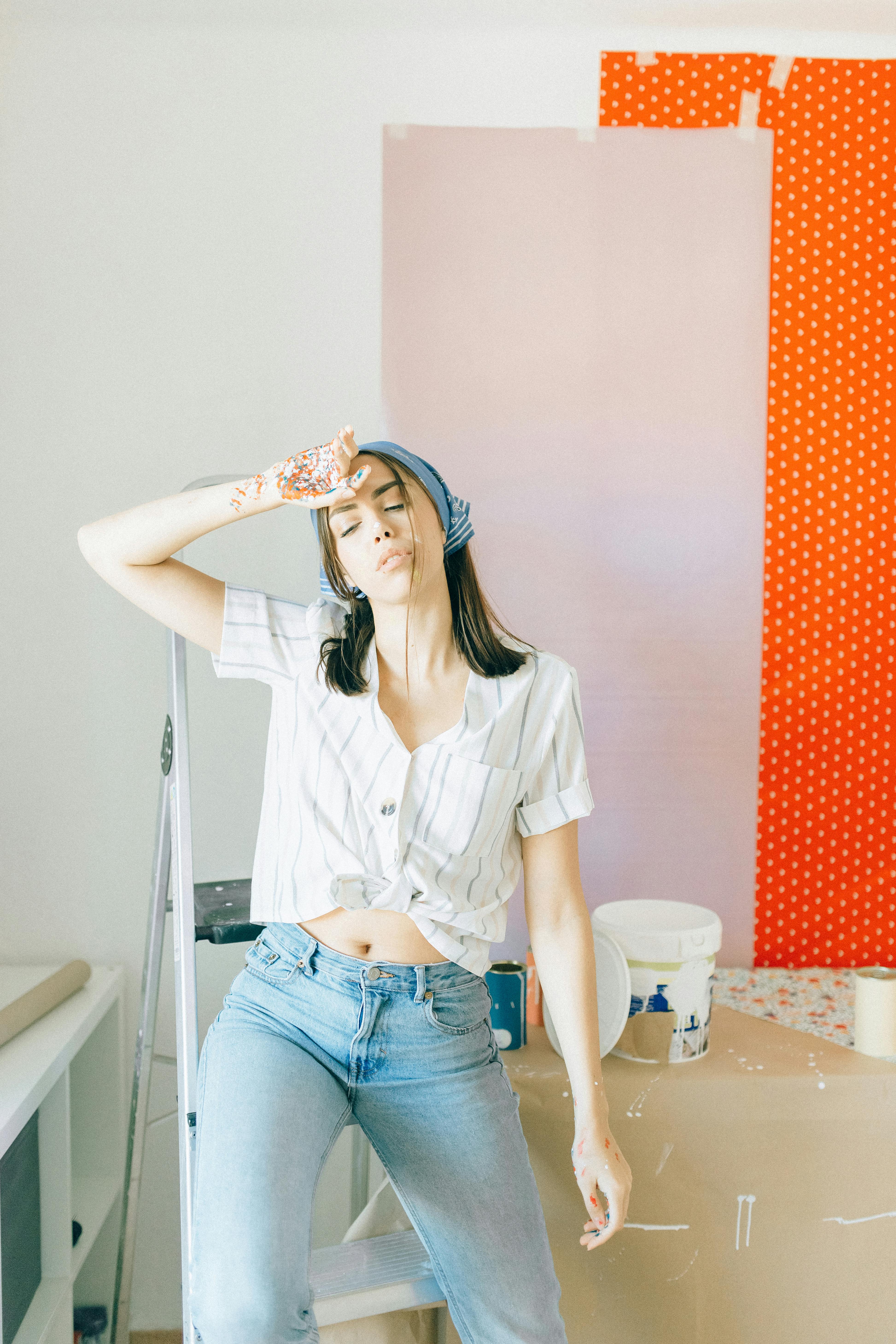 woman in white button up shirt and blue denim jeans sitting on white ceramic toilet bowl