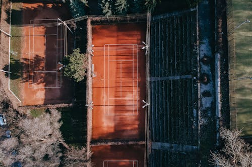 Aerial view of modern sports fields with marking and seats for fans under sunlight