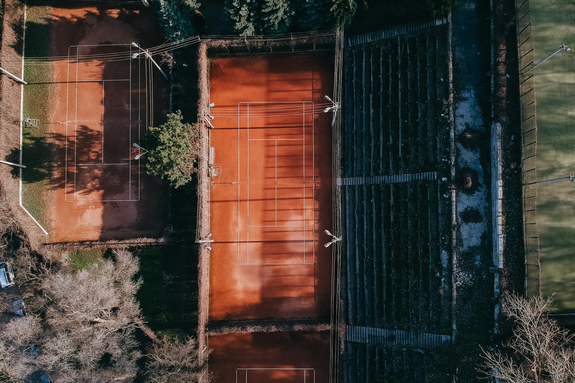 Aerial view of modern sports fields with marking and seats for fans under sunlight