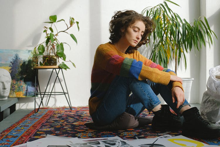 Lady Sitting Near Paintings On Floor In Studio