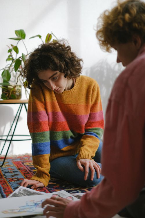 Free Young artists working on new creative project sitting on floor and watching pictures in room Stock Photo