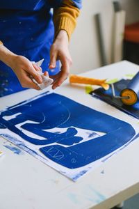 Hands carving a blue lino plate, by Anna Shvets on Pexels