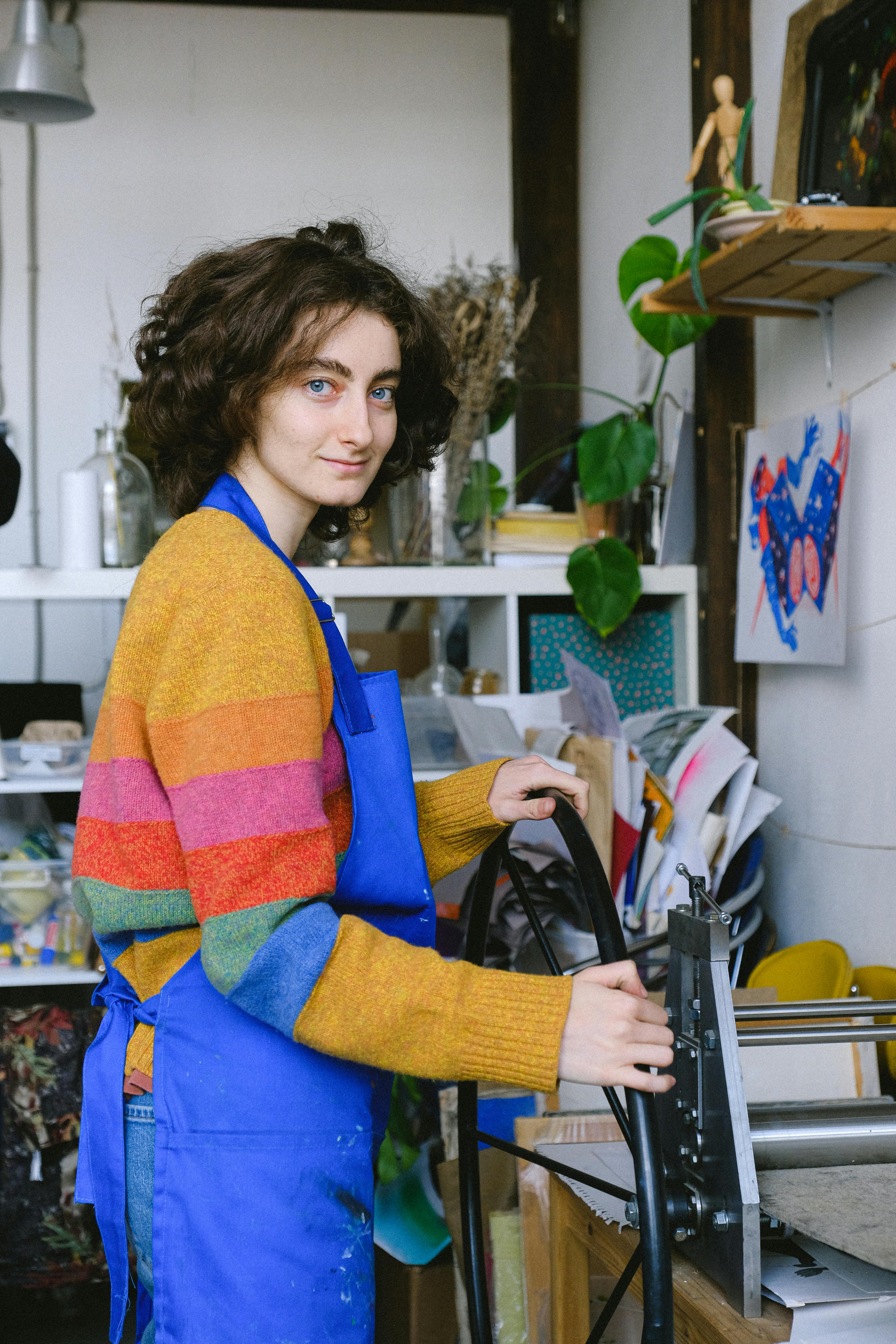 young craftswoman printing etching picture on press machine