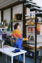一名穿着彩色毛衣的女人正在一个组织严密的艺术工作室里制作作品