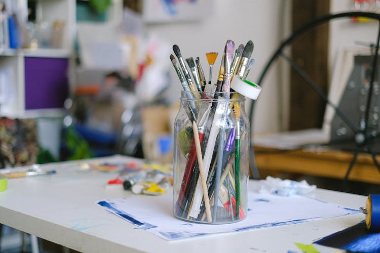 Paint Brushes In Glass Jar On Table In Painter Craft Shop