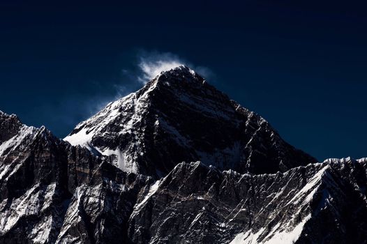 白雪皑皑的山峰在黑暗的天空下投下巨大的阴影，景色壮丽
