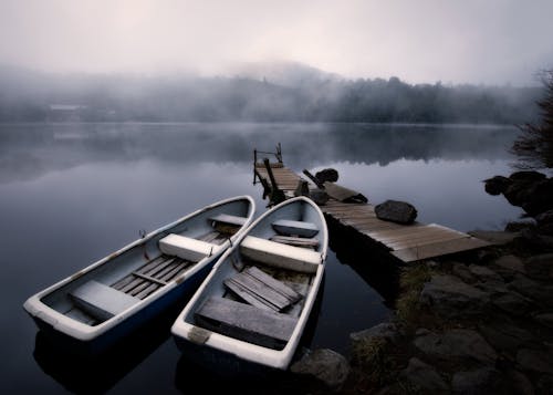 Boats near pier on lake in fog