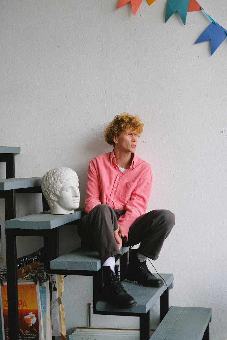 Unhappy Man Sitting On Staircase With Bust