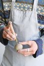 Unrecognizable male potter wearing apron standing with piece of clay in hand and sharp tool while  working in professional studio