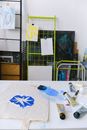 Bag with blue print placed on white table with paintbrush and set of tubes for painting in creative workshop with paintings