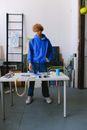 Full body of concentrated male designer with brush mixing paints while working with stencil printing at table with bag in art studio