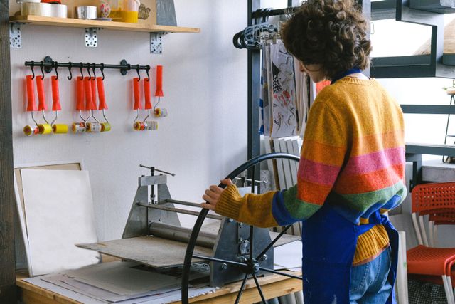 Printmaker at a workbench pulling a print — Anna Shvets on Pexels