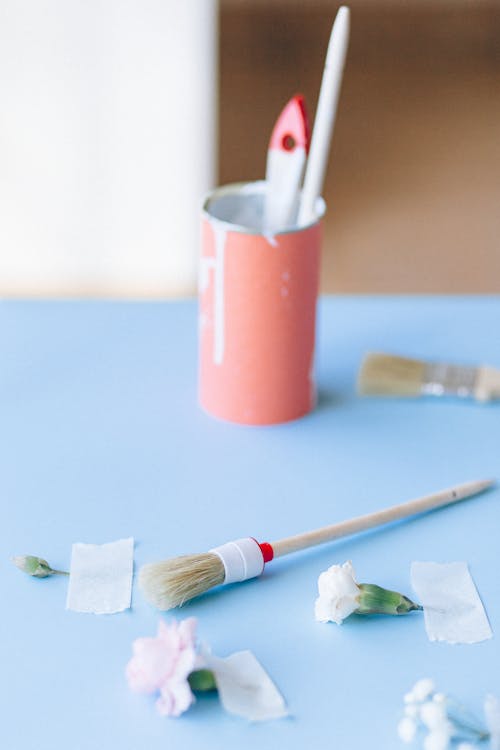 Close-Up Shot of a Paint Brush and Taped Flowers near a Can