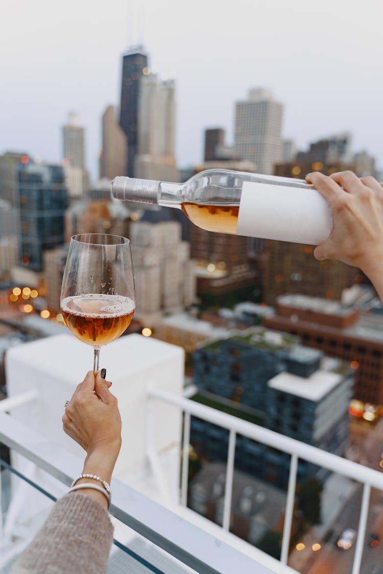 Person Pouring Wine On Clear Drinking Glass