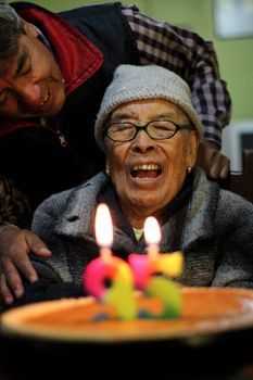 Senior woman joyfully celebrating her birthday with candles and cake.