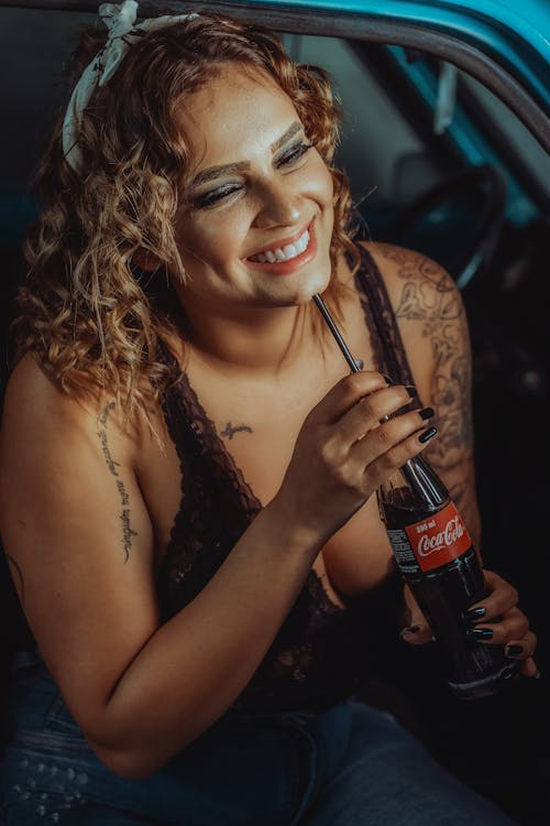 Close-Up Shot of a Blonde Woman Holding a Bottle of Coke