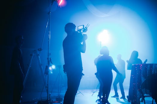 Cinematic night scene showcasing filming crew and silhouetted performers in vibrant light.