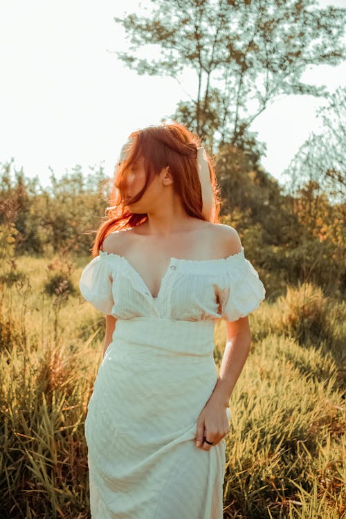 Young woman with long red hair in long summer dress