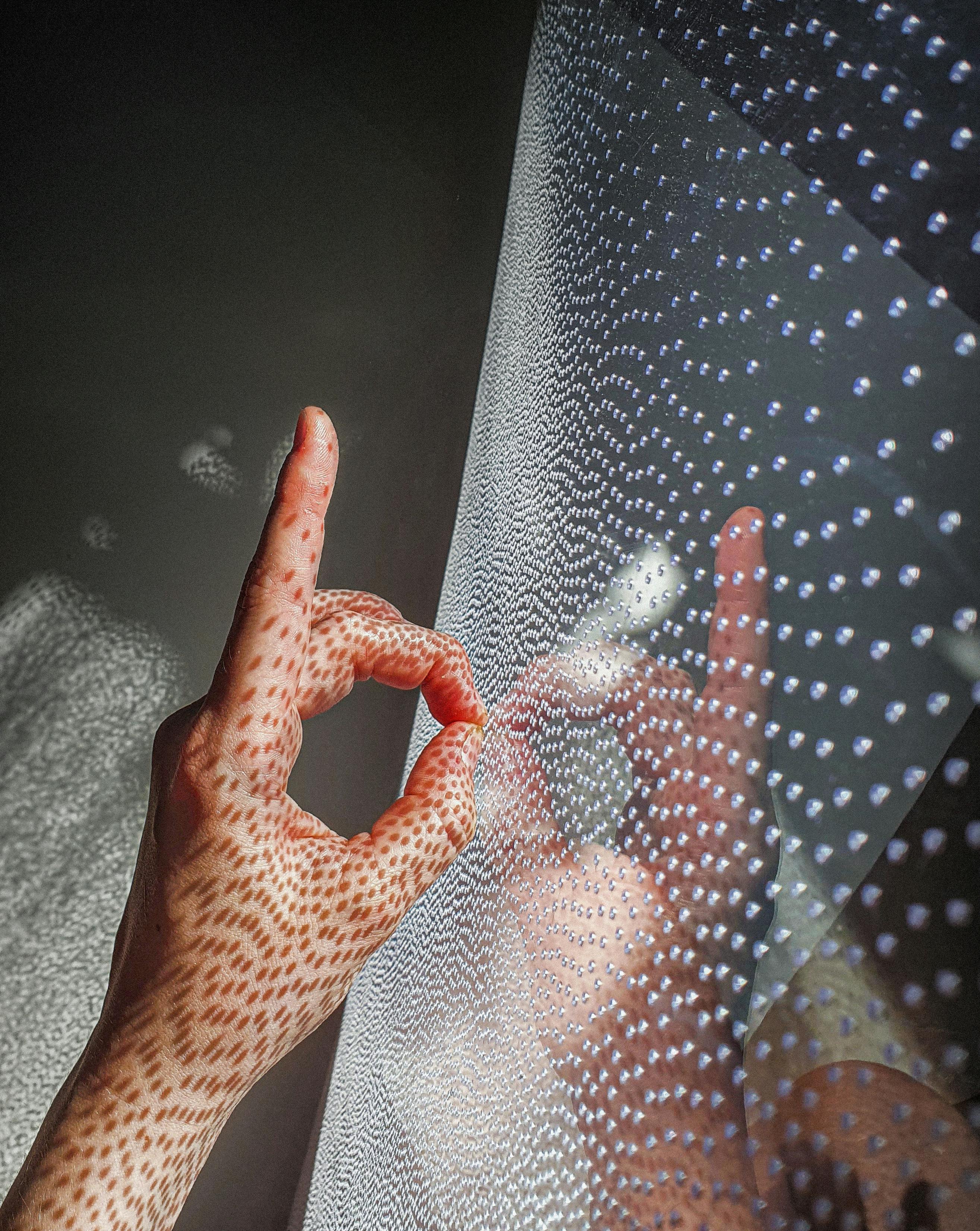 A hand making a gesture with intricate patterns reflected in light.