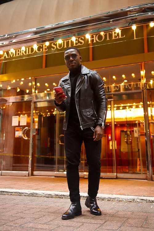 A Man in a Leather Jacket Standing Outside the Hotel