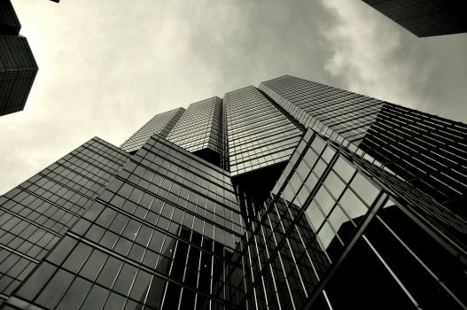 Low-angle shot of a modern skyscraper with glass facade in monochrome.