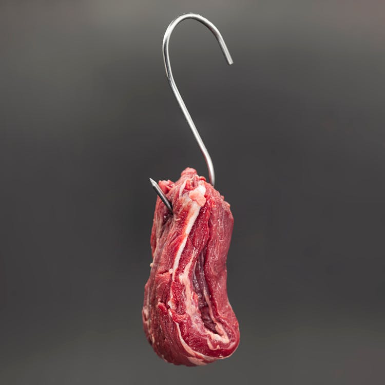 Raw Meat Hanging On A Metal Hook