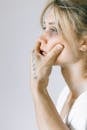 Woman in White Shirt Covering Her Face With Her Hand