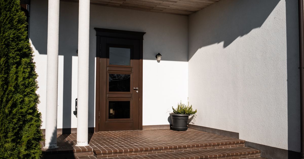 Contemporary house entrance featuring brown door, brick steps, and decorative columns.