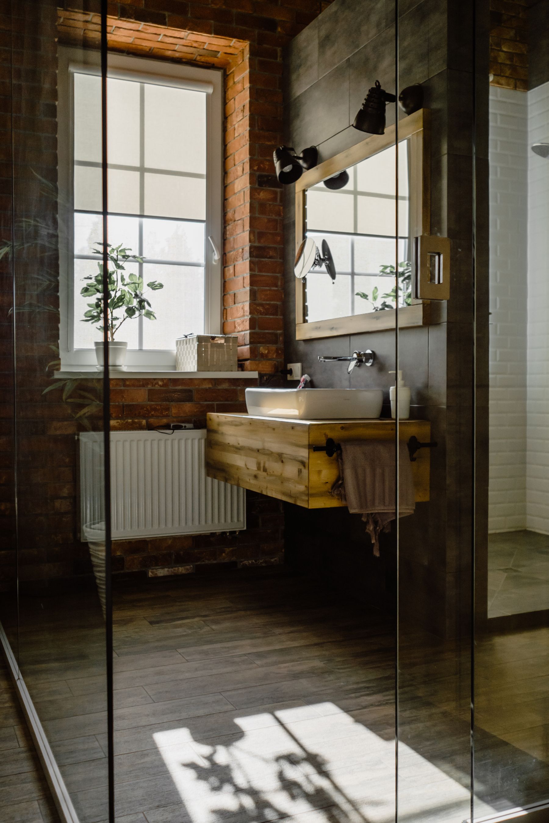 Bathroom with brick wall, warm wood and restrained industrial materials
