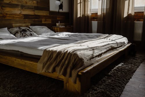A Wooden Bed Frame with Mattress and Blanket