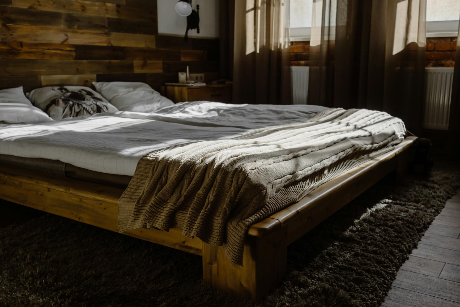 A Wooden Bed Frame with Mattress and Blanket