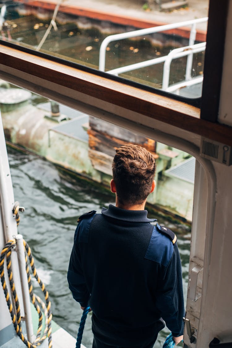 Faceless Man Standing On Boat In Sea