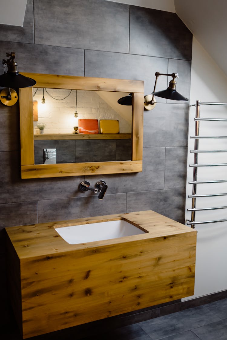 Brown Wooden Framed Mirror Hanging On The Gray Wall 