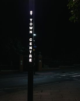 Street sign for town centre illuminated in darkness, providing guidance at night.