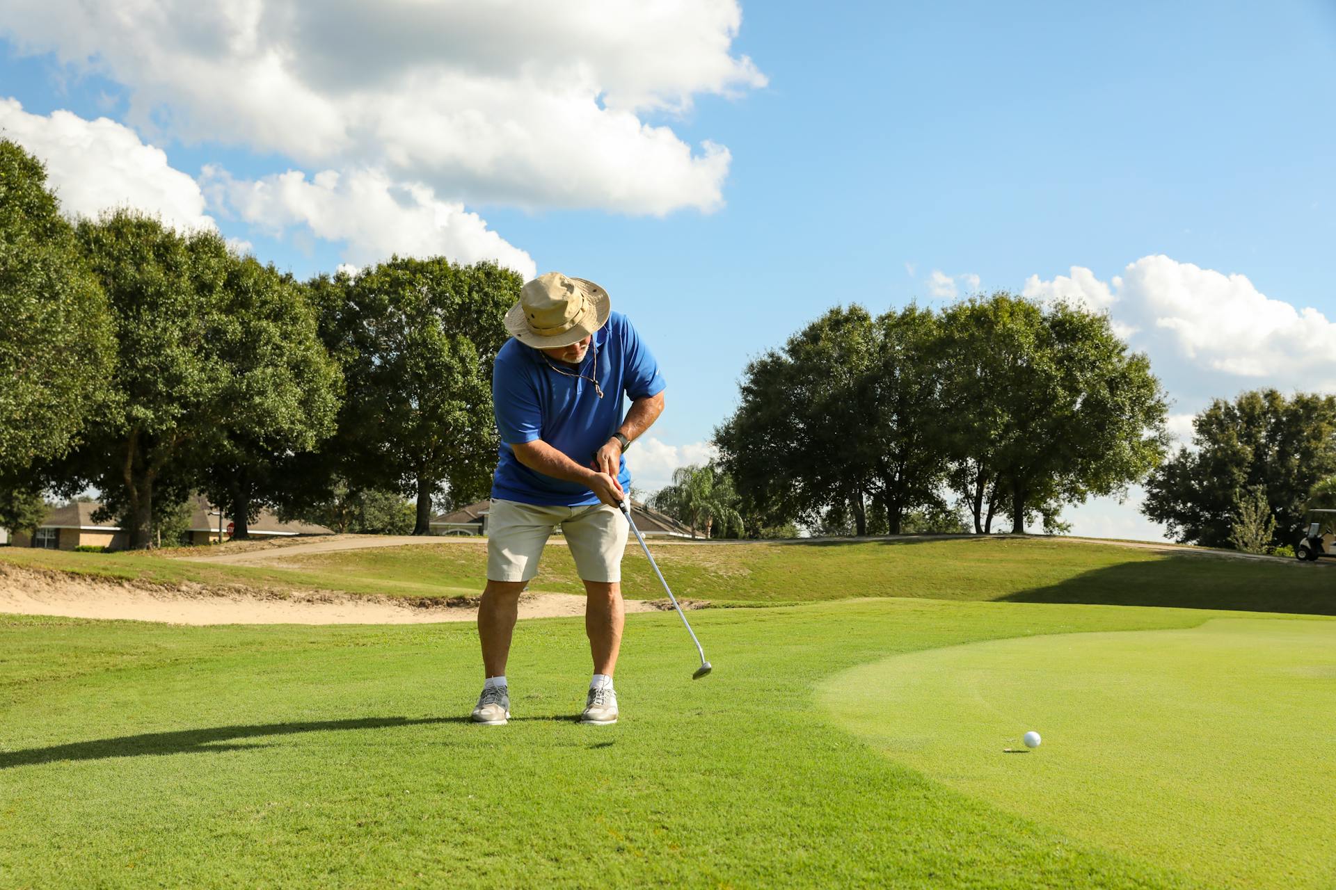 An adult male golfer putting on a lush golf course in Eustis, Florida under a bright sky.