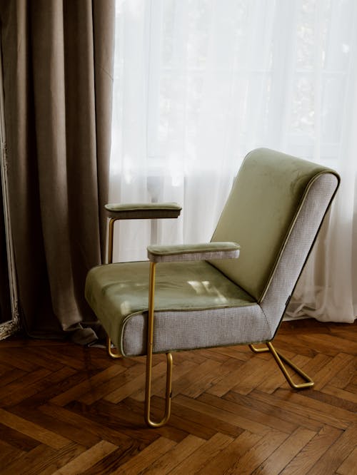 棕色窗簾旁邊的灰色皮革軟墊椅子