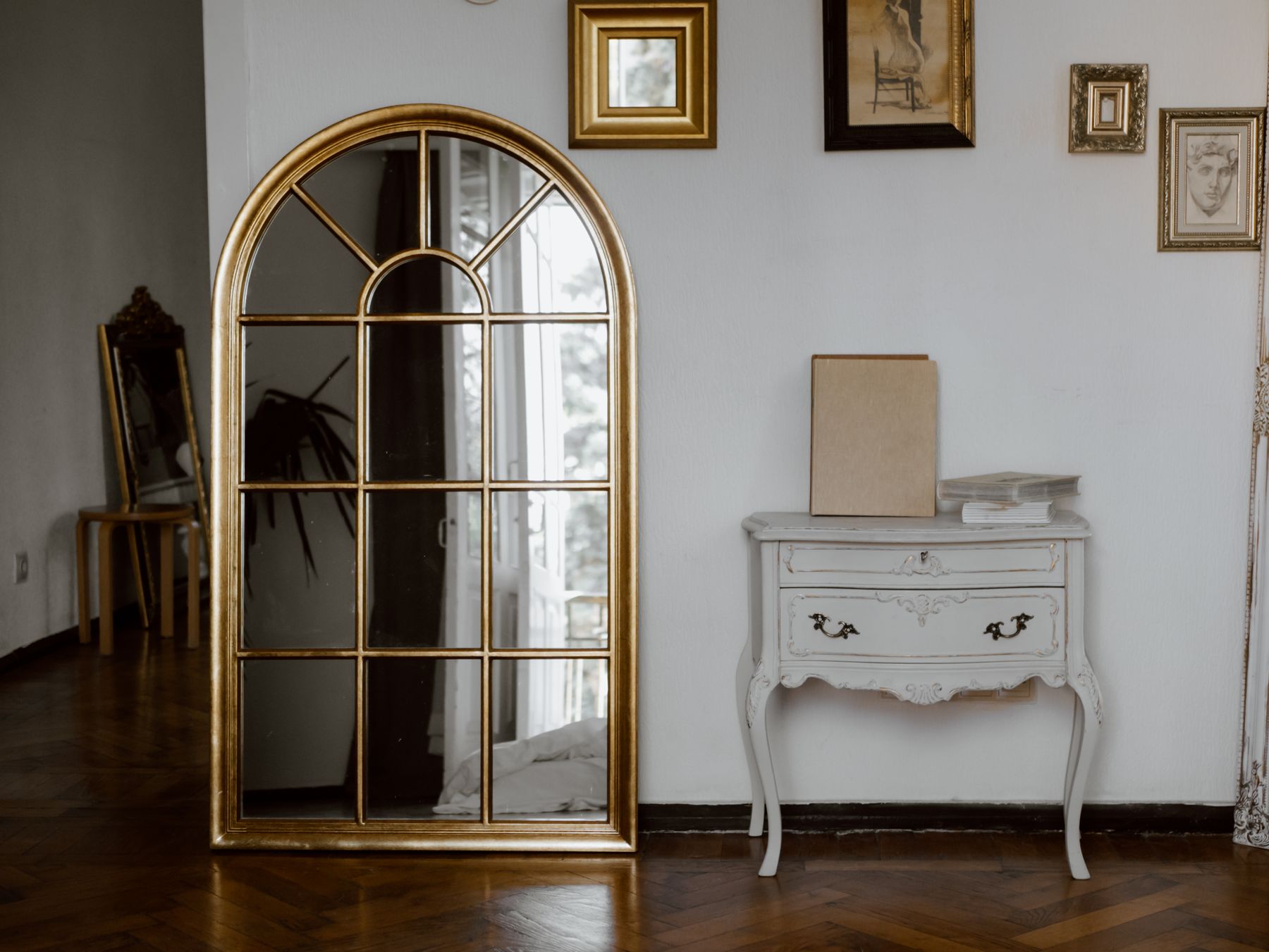 Classic white console table beneath a tall arched gold mirror